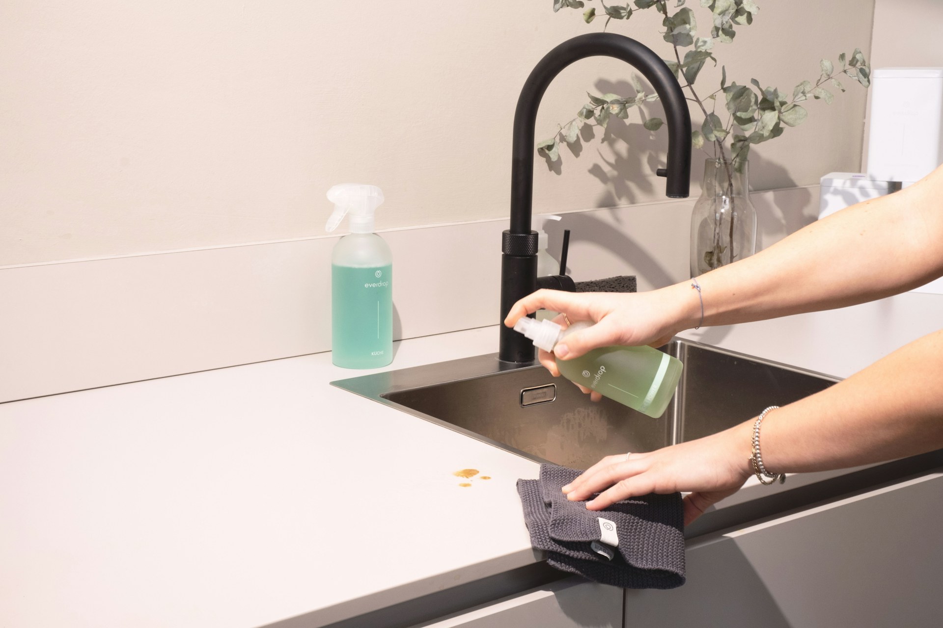 A woman cleans a kitchen sink with a cloth